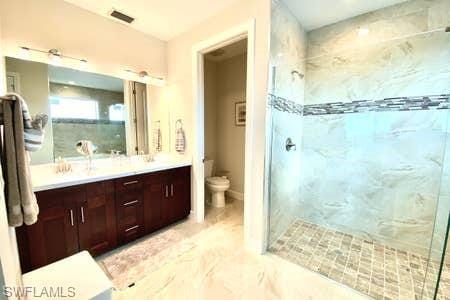 bathroom with toilet, a shower with door, large vanity, and tile floors