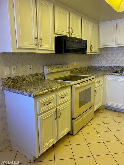 kitchen featuring white cabinets, backsplash, light tile flooring, and white electric stove