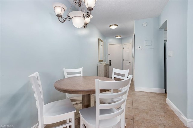 tiled dining area featuring a textured ceiling and a notable chandelier