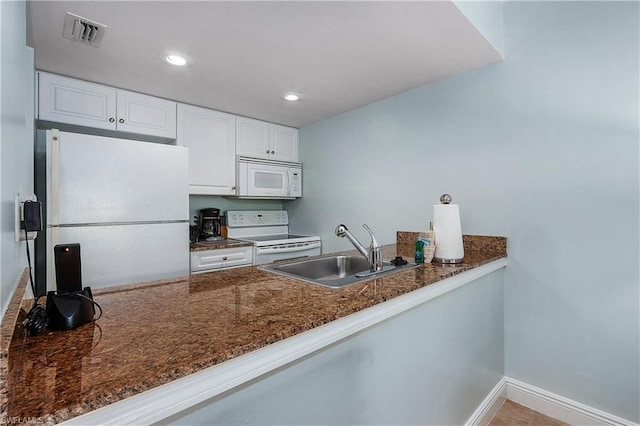 kitchen featuring kitchen peninsula, white appliances, sink, dark stone countertops, and white cabinets