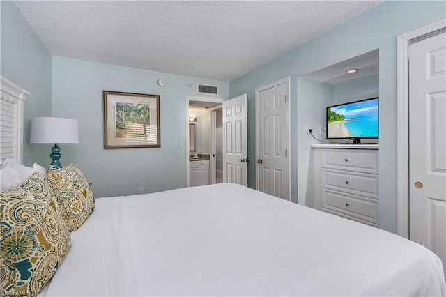 bedroom featuring ensuite bath and a textured ceiling