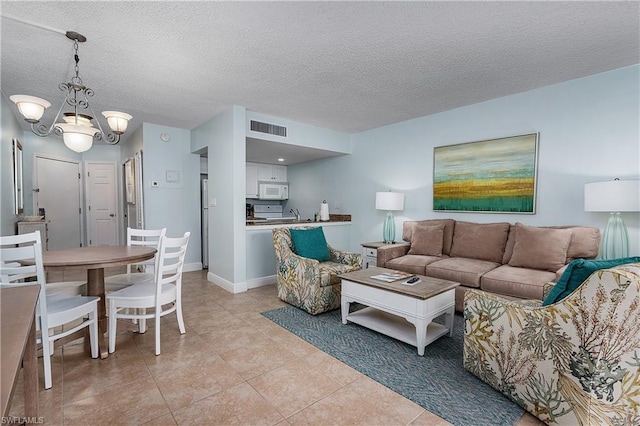 living room featuring light tile floors, a notable chandelier, and a textured ceiling