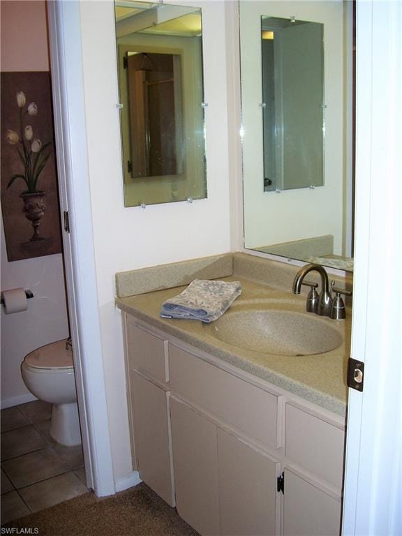 bathroom featuring toilet, vanity, and tile flooring