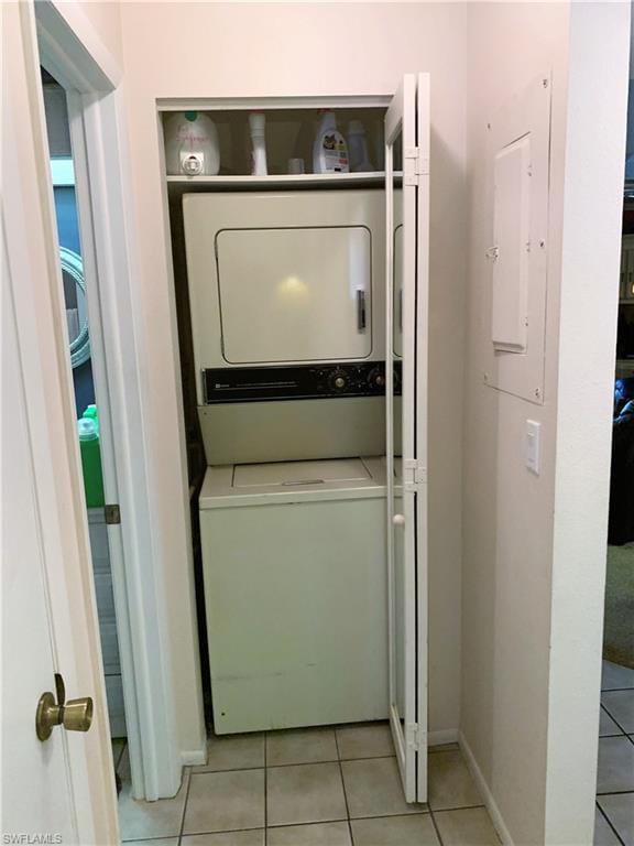 laundry room with stacked washing maching and dryer and light tile floors