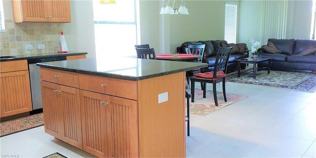 kitchen with backsplash, a kitchen island, an inviting chandelier, and light tile flooring