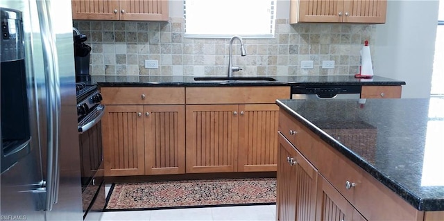 kitchen featuring backsplash, tile floors, sink, stainless steel appliances, and dark stone counters