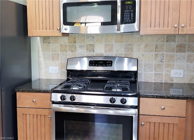 kitchen with tasteful backsplash, stainless steel appliances, and dark stone countertops