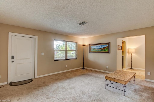 unfurnished room featuring light colored carpet and a textured ceiling