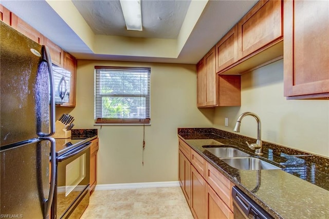 kitchen featuring black refrigerator, sink, light tile floors, range with electric stovetop, and dark stone counters