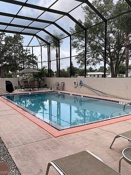 view of swimming pool featuring a patio area and glass enclosure