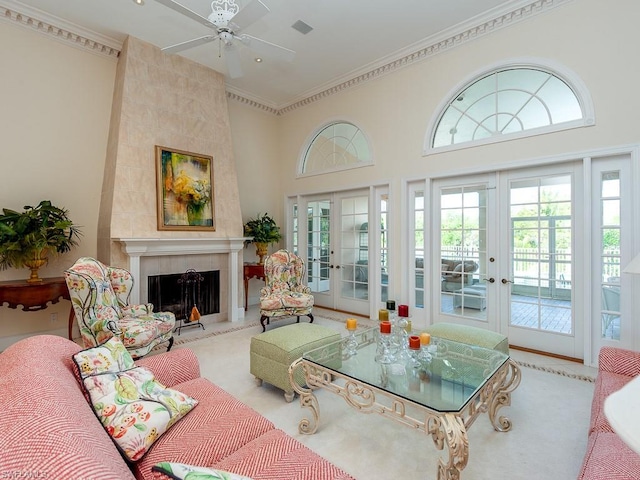 carpeted living room featuring a tile fireplace, ceiling fan, french doors, and crown molding