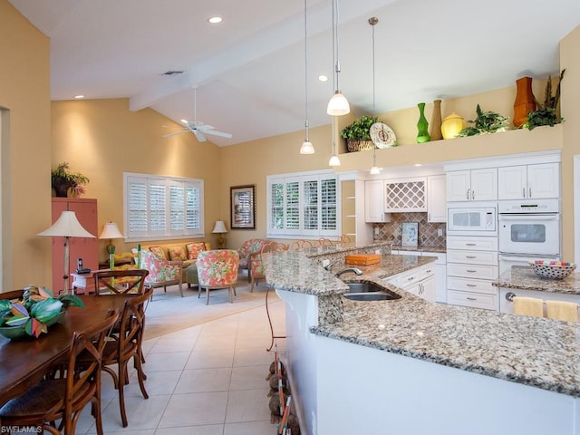 kitchen with white appliances, pendant lighting, ceiling fan, light stone counters, and white cabinetry