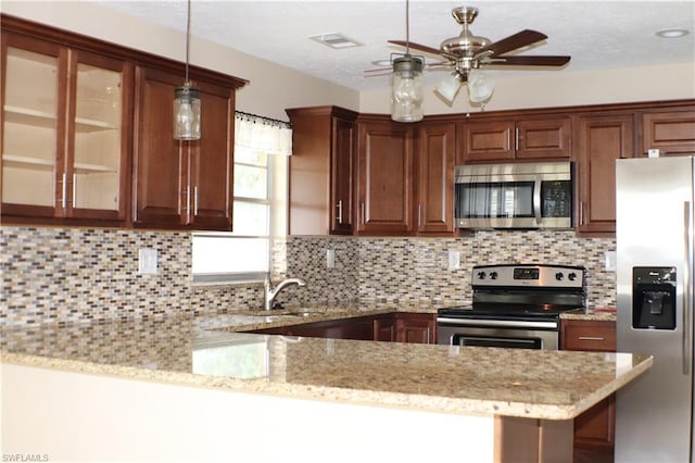 kitchen featuring kitchen peninsula, pendant lighting, ceiling fan, appliances with stainless steel finishes, and backsplash