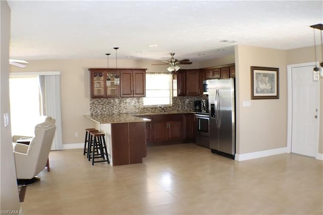 kitchen featuring kitchen peninsula, stainless steel fridge, pendant lighting, ceiling fan, and range