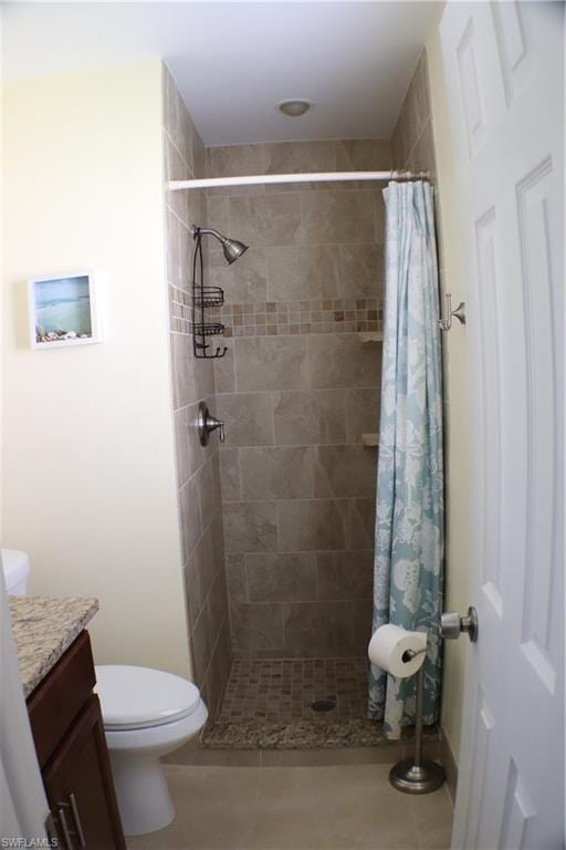 bathroom with tile floors, toilet, vanity, and a shower with shower curtain