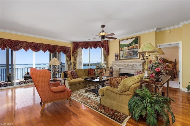 living room with a water view, light hardwood / wood-style floors, ceiling fan, and crown molding