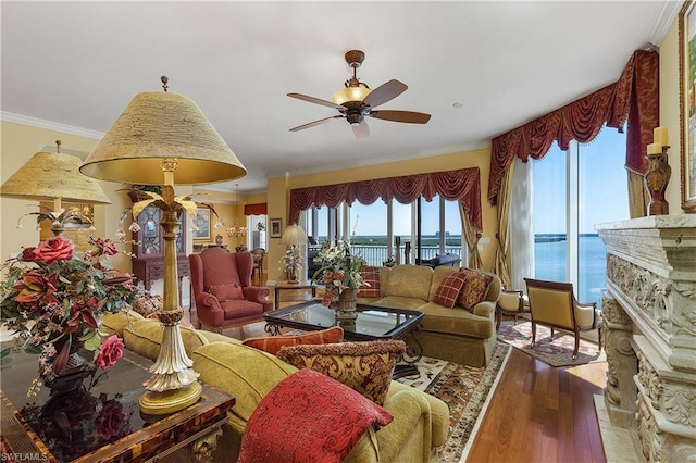 living room with ceiling fan, crown molding, a fireplace, a water view, and light wood-type flooring