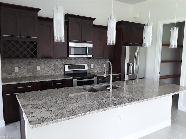 kitchen with hanging light fixtures, sink, stainless steel appliances, light stone counters, and tasteful backsplash