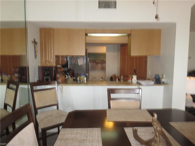 kitchen featuring light brown cabinetry and black refrigerator