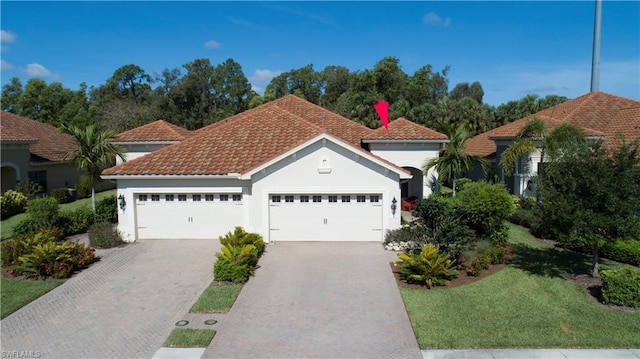 mediterranean / spanish-style home featuring a front yard and a garage