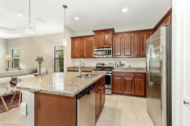 kitchen featuring sink, light stone counters, hanging light fixtures, a center island with sink, and stainless steel appliances