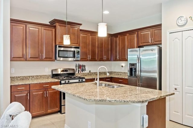 kitchen featuring pendant lighting, stainless steel appliances, light tile flooring, a kitchen island with sink, and sink