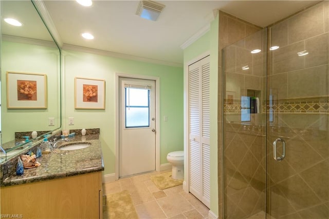 bathroom featuring a shower with door, tile flooring, vanity with extensive cabinet space, toilet, and crown molding