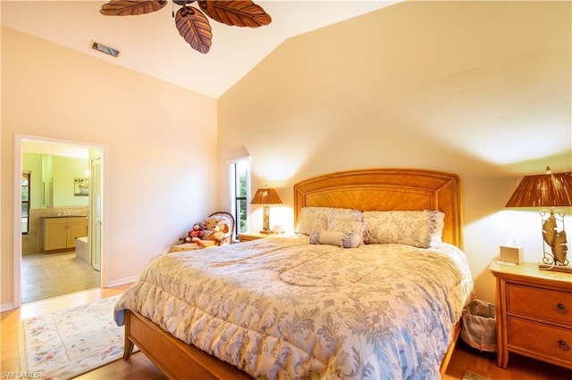 bedroom with light tile floors, ensuite bath, ceiling fan, and vaulted ceiling