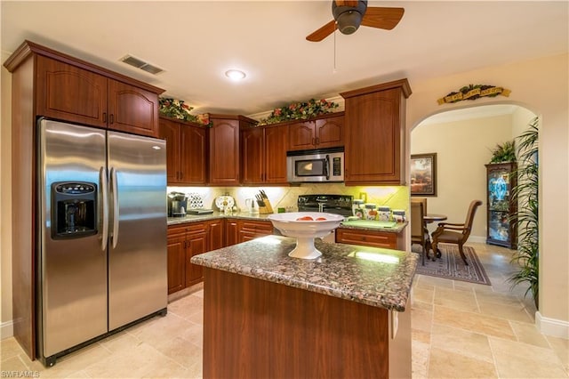 kitchen with light tile floors, dark stone counters, ceiling fan, appliances with stainless steel finishes, and backsplash