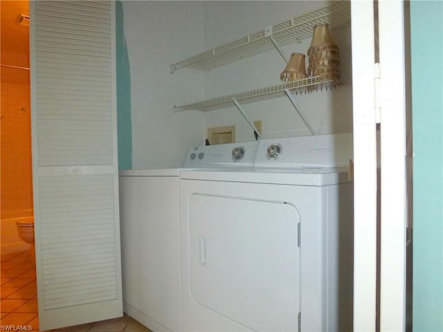 clothes washing area with washer hookup, washer and dryer, and light tile flooring