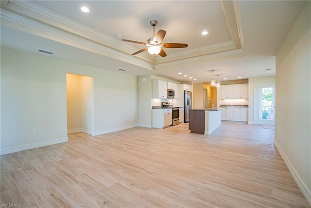 unfurnished living room with ceiling fan, light hardwood / wood-style floors, sink, a raised ceiling, and crown molding