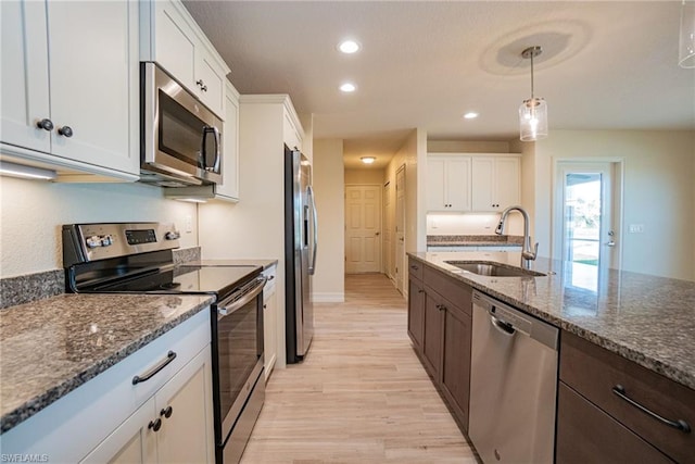 kitchen with light hardwood / wood-style floors, stainless steel appliances, decorative light fixtures, white cabinetry, and sink