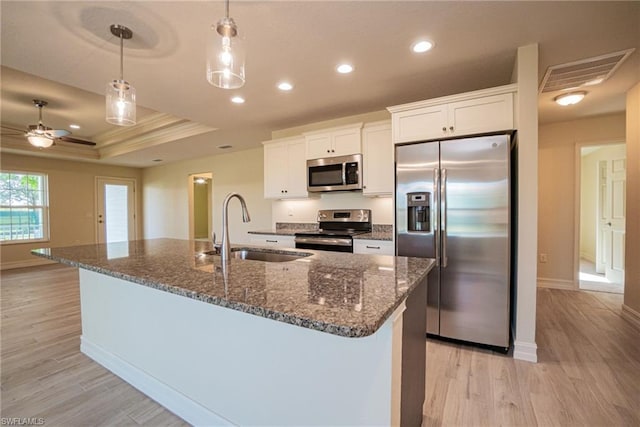 kitchen featuring sink, light hardwood / wood-style flooring, stainless steel appliances, white cabinets, and a raised ceiling