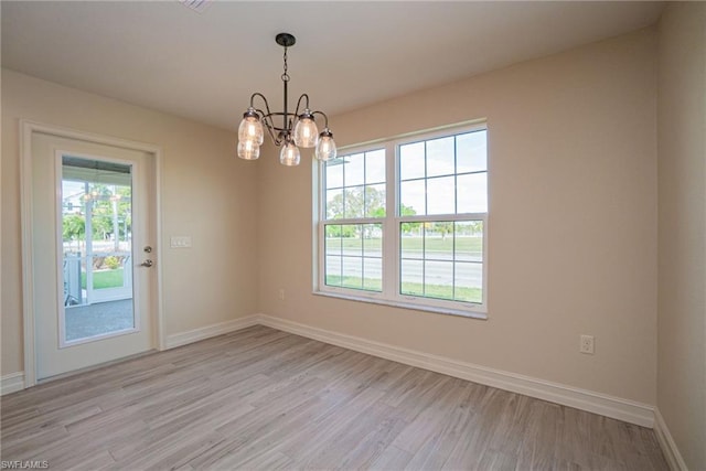 spare room featuring light hardwood / wood-style flooring, plenty of natural light, and a notable chandelier