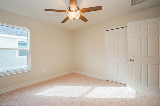 unfurnished bedroom with a closet, light colored carpet, and ceiling fan