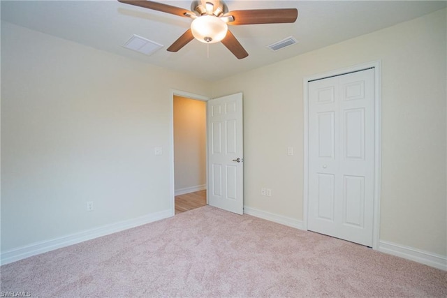 unfurnished bedroom featuring a closet, light colored carpet, and ceiling fan