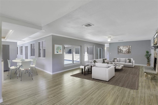 living room featuring ornamental molding, ceiling fan, hardwood / wood-style flooring, and a fireplace