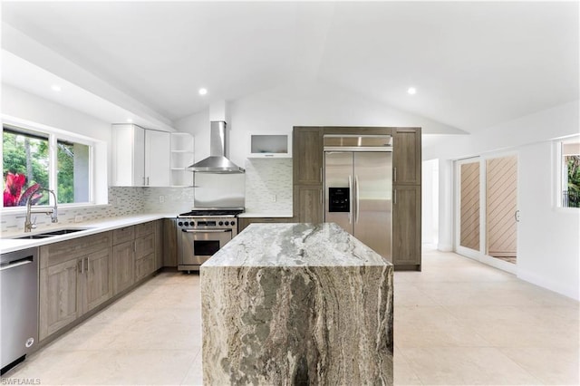 kitchen featuring sink, light tile floors, white cabinets, high end appliances, and wall chimney exhaust hood