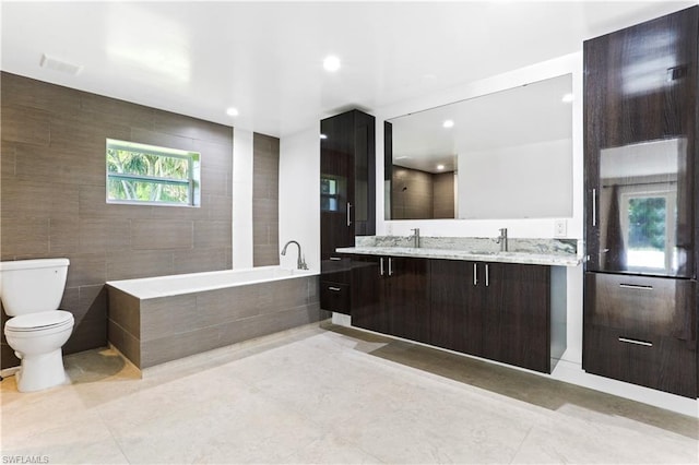 bathroom featuring tile walls, toilet, double sink vanity, tile flooring, and a tub