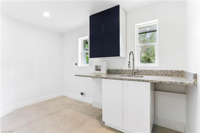 kitchen featuring white cabinetry, light tile floors, sink, and light stone counters