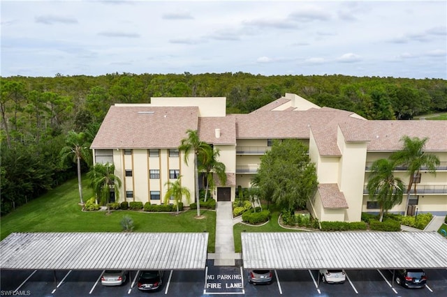 back of property featuring a balcony, a lawn, and a carport