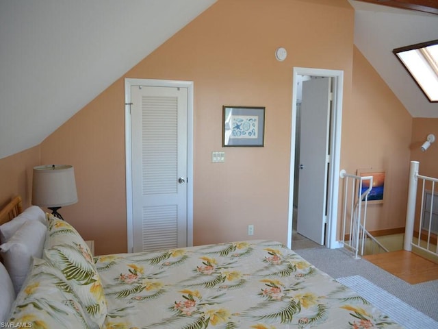 carpeted bedroom with a closet and vaulted ceiling with skylight