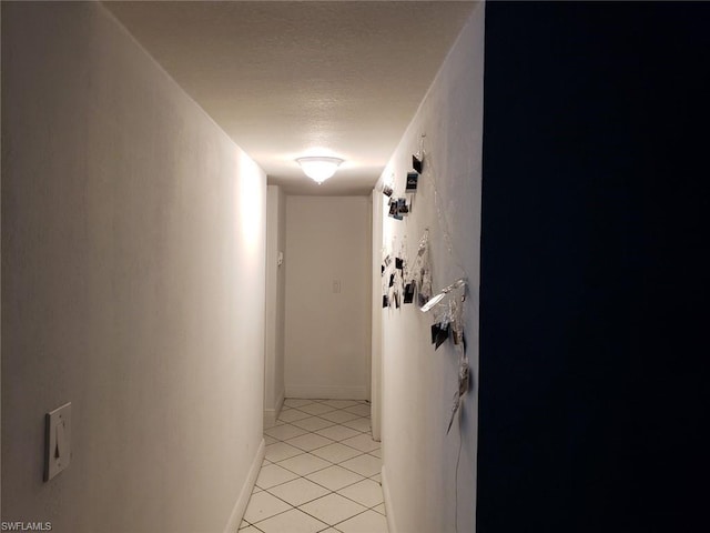 corridor featuring a textured ceiling and light tile floors