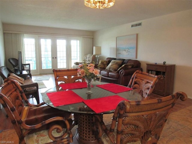 tiled dining area featuring a notable chandelier and french doors