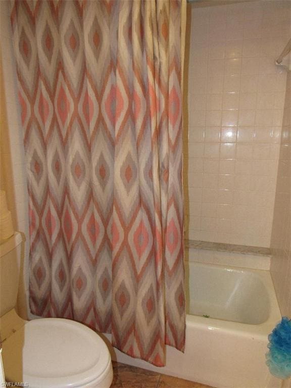 bathroom with toilet, tile floors, and shower / bath combination with curtain