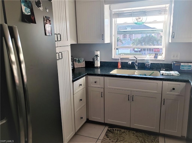 kitchen with stainless steel fridge, light tile flooring, white cabinets, and sink