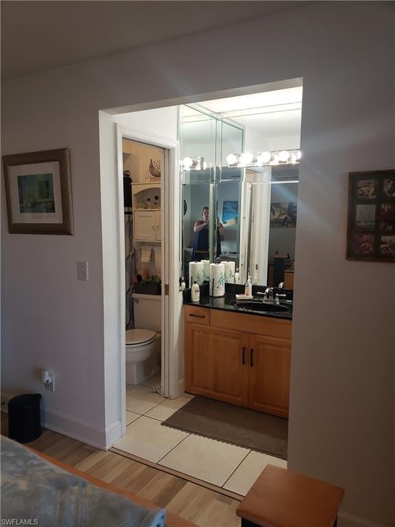 bathroom featuring a notable chandelier, vanity, tile flooring, and toilet