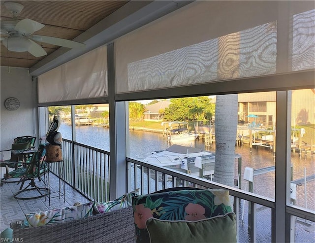 sunroom with ceiling fan and a water view