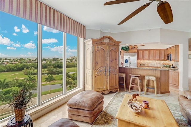 tiled living room featuring crown molding and ceiling fan