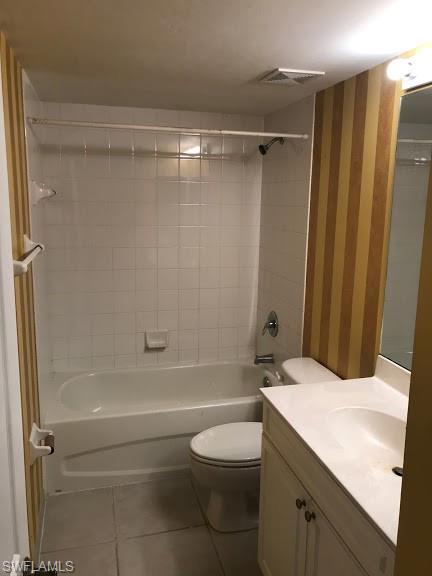 full bathroom featuring tiled shower / bath combo, toilet, vanity with extensive cabinet space, and tile flooring